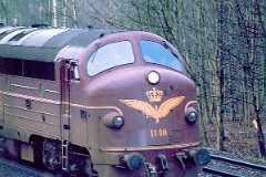 DSB MY 1140 heading for Fredericia. Photographed in Hannerup Skov, Fredericia, March 1975.   The MY class was built by Nydquist & Holm AB (NOHAB) in Sweden licensed by General Motors. Danish subsuppliers (Frichs and Thrige) took part in the production. A1A-A1A. Dieselelectric. MY 1101 - 1105 was supplied with a General Motor 16-cyl. diesel engine performing 1.700 hp. The diesel engine in MY 1106 - 1144 was performing 1.950 hp - MY 1145 - 1159 1700 hp. Max speed 133 km/h - 83 mph. Length 18 900 mm. Weight 101,6 metric tonnes. MY 1140 was put in service in 1958. It was taken out of service in 1987 because of a fire in the electric system. It was scrapped in 1989.